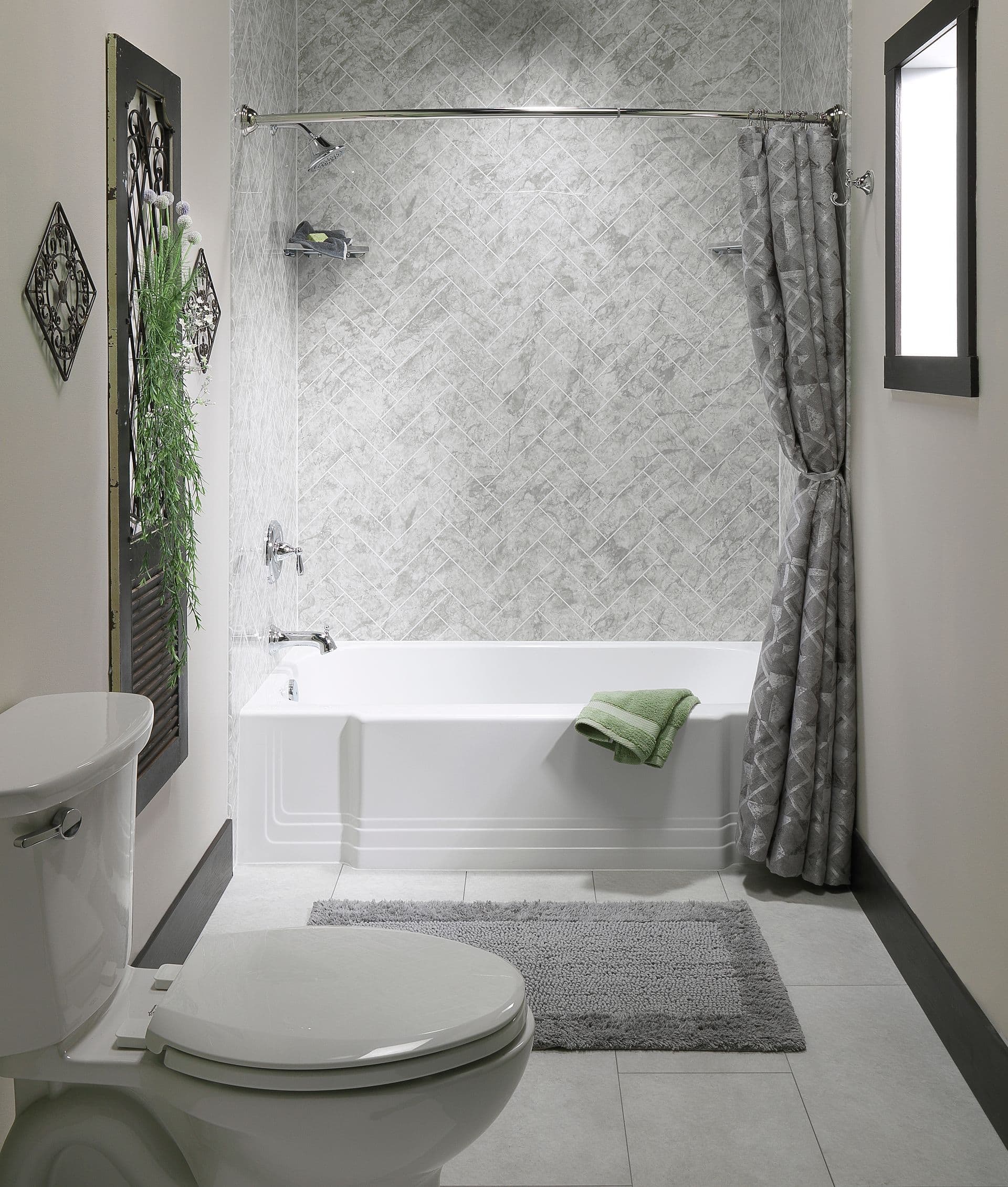 Modern bathroom featuring a white alcove bathtub with a gray herringbone-pattern wall surround, chrome shower fixtures, gray tile flooring, a matching shower curtain, and neutral décor with black trim accents.