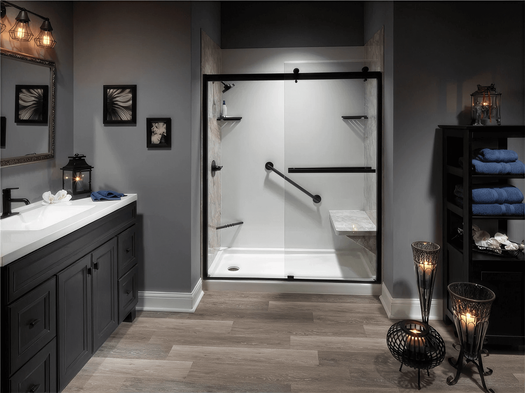 Modern walk-in shower with a sleek black-framed sliding glass enclosure, built-in bench, grab bars, and minimalist white shower walls, paired with dark cabinetry and contemporary finishes for a stylish, accessible bathroom.