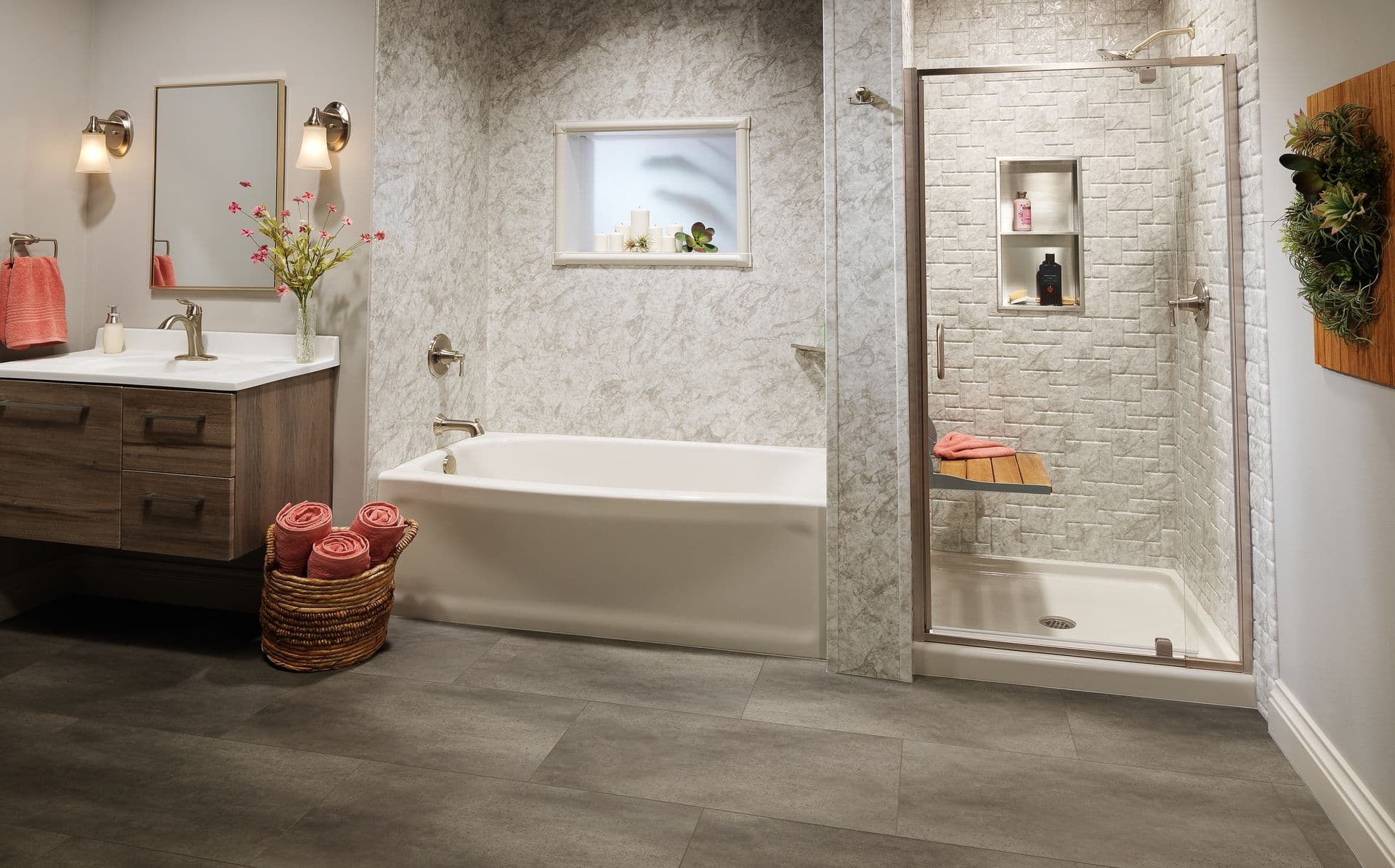 Modern bathroom featuring a floating wood vanity, white soaking tub, stone-look shower with built-in niche and bench, and large-format gray tile flooring.