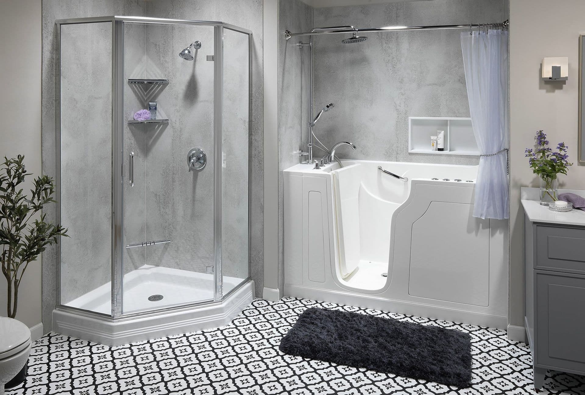 Accessible bathroom with a walk-in tub, corner glass shower, textured gray wall panels, patterned tile flooring, and a gray vanity.